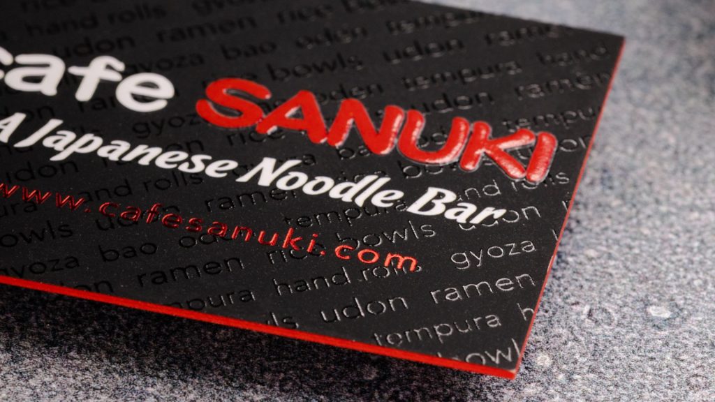 black embossed business card for a Japanese noodle bar with raised red print