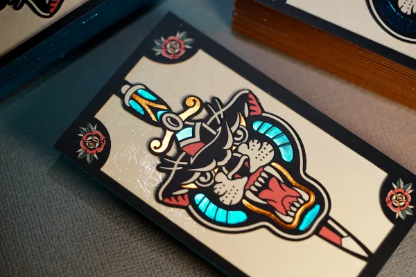 A black and cream card with teal and copper metallic foil illustration.