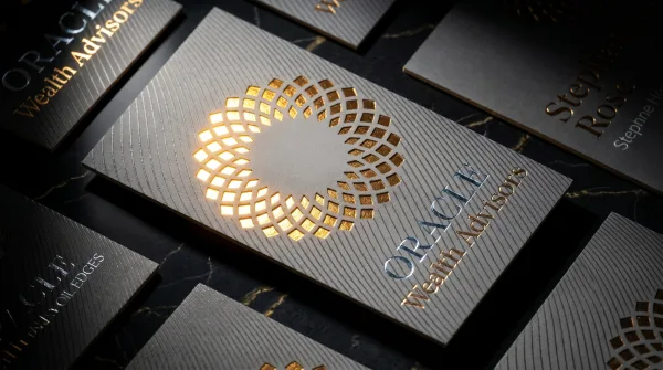 A smooth silk-laminated gray card with a laser-cut gold sunburst logo.