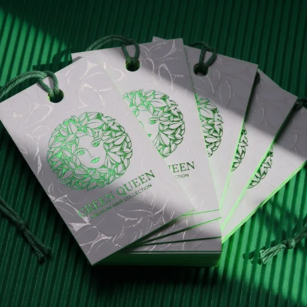 A fanned stack of gray hang tags with green foil lettering, showing the multi-board edge thickness.