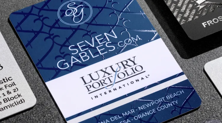 A navy "Seven Gables" Luxury Portfolio International real-estate card for Corona Del Mar, Newport Beach, Costa Mesa, and Orange County.